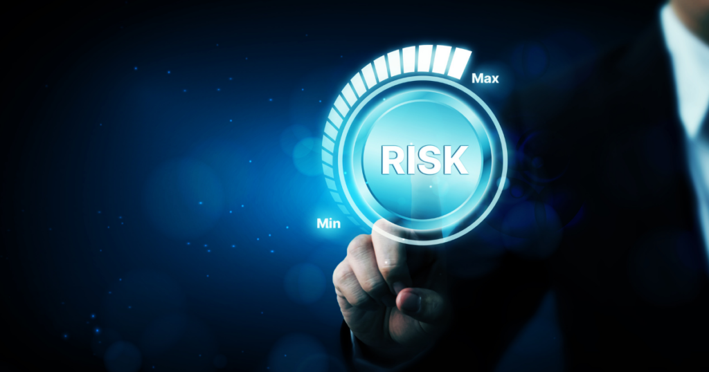 A finger touching a dial that has max and min written on it, with the word risk in the middle.